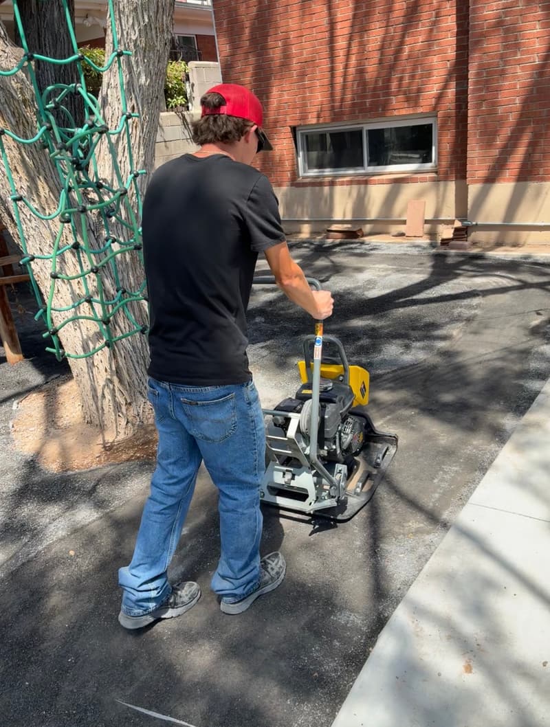 Plate compactor tamping a gravel base during hardscape site prep in Albuquerque