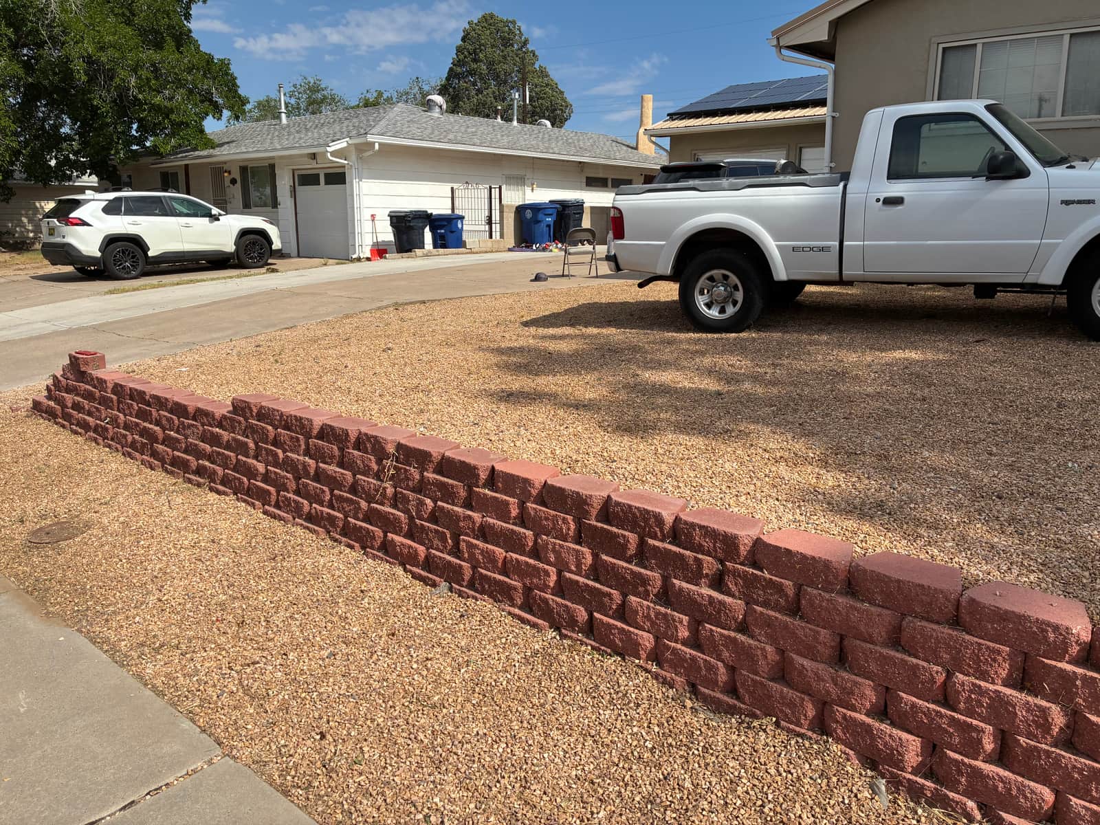 Finished red block retaining wall along a driveway in an Albuquerque front yard