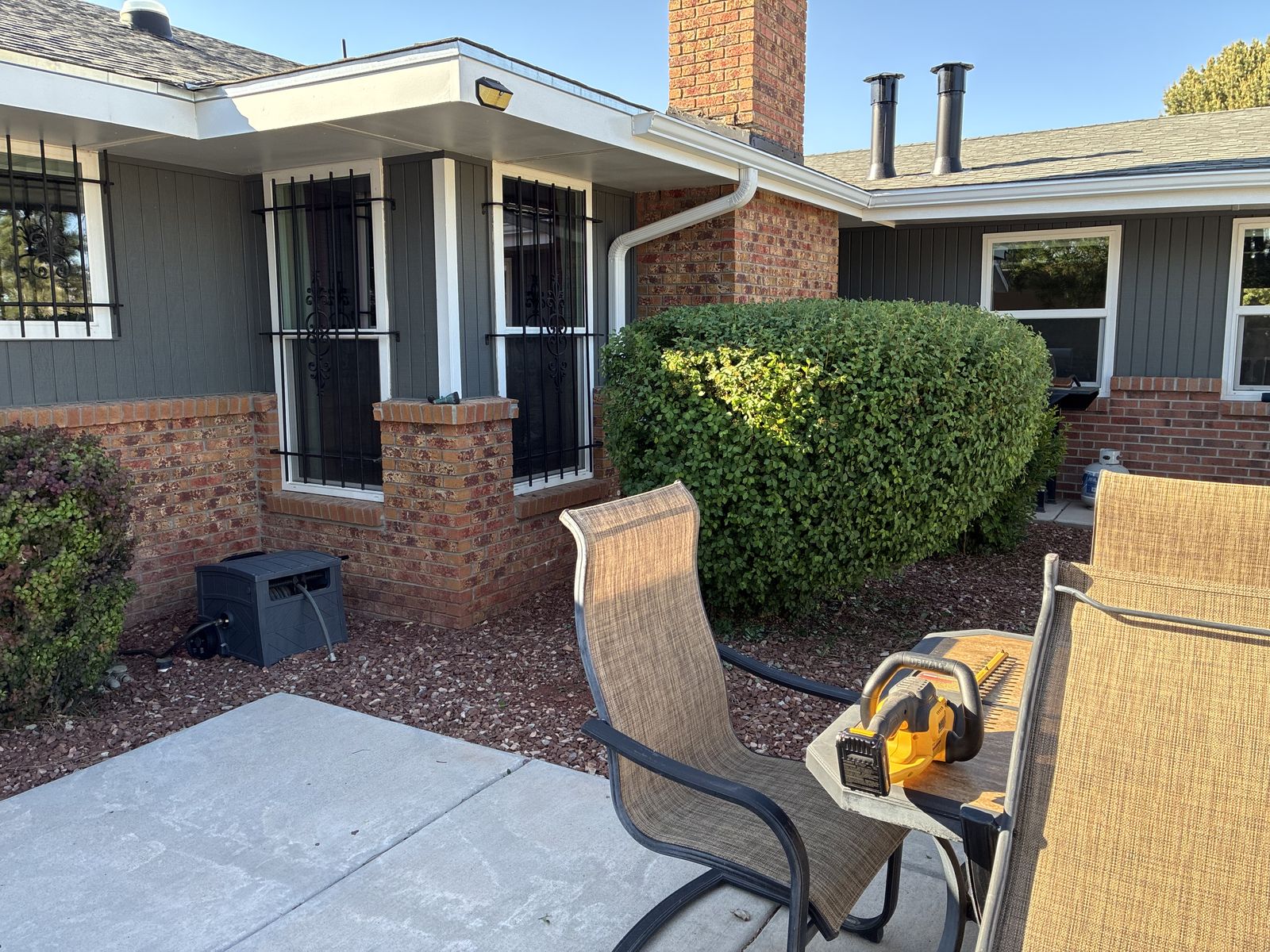 Squared hedge next to a brick and siding home