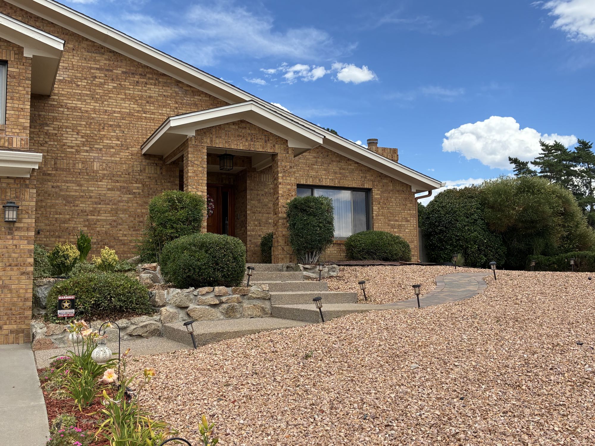 Xeriscaped front yard with gravel, paver walkway, and stone steps in Albuquerque